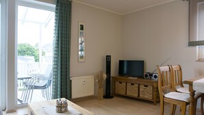 Un salon avec une table en bois, un téléviseur, une radio et un fauteuil.