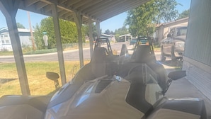 A futuristic vehicle with a sleek design, parked under a covered area. - Almost paradise (Coeur d'Alene)