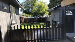 A residential backyard with a wooden fence, a grassy lawn, and a concrete patio. - Almost paradise (Coeur d'Alene)