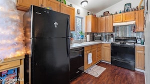 A kitchen with wooden cabinets, a black refrigerator, a stove, and a microwave. - Almost paradise (Coeur d'Alene)