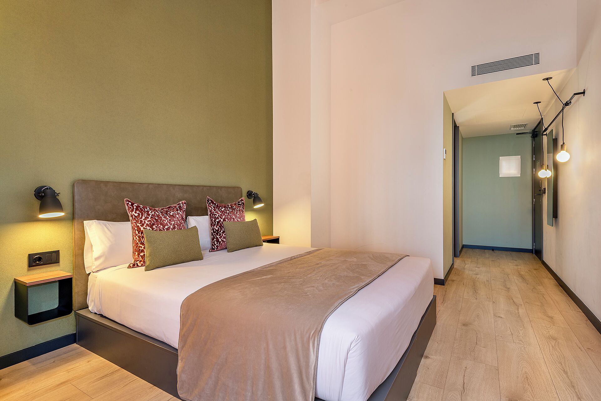 Ein Hotelzimmer mit Bett, Nachttischlampen, einem Nachttisch und Holzboden.