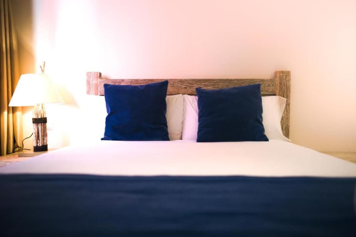 A bed with a wooden headboard, two pillows, and a bedside lamp.