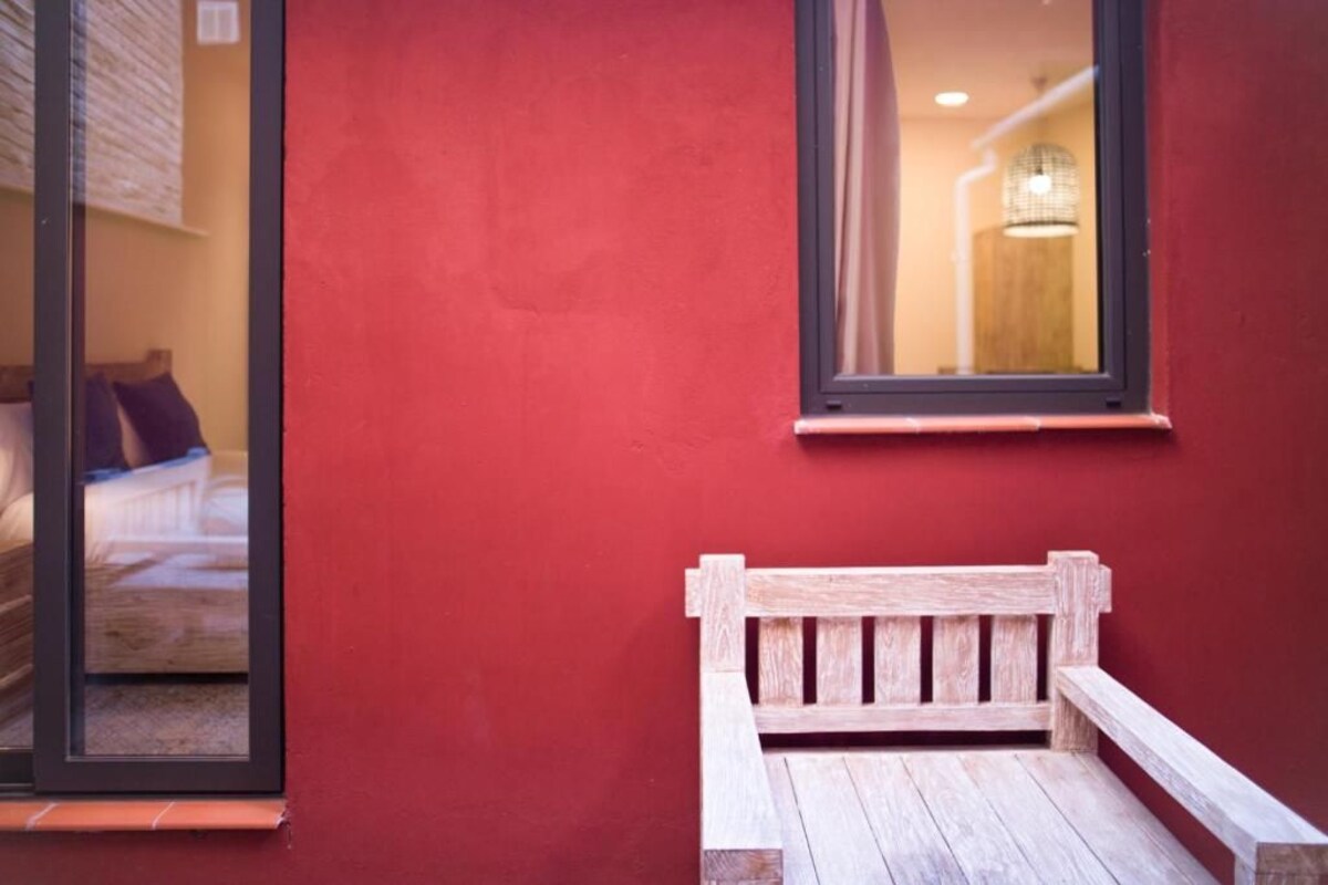 Eine rote Wand mit einer Holzbank und einem Fenster.