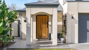 Una casa moderna con puerta principal de madera, un porche cubierto y un garaje.