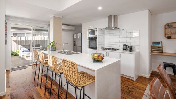 Una cocina moderna con una isla central, electrodomésticos de acero inoxidable y vistas a un balcón.