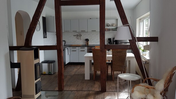 A modern kitchen with white cabinets, a dining area with a white table and chairs, and a wooden-framed doorway leading to another room. - Vacation apartment in Wermelskirchen, Bergisches Land, near Cologne and Düsseldorf (Wermelskirchen)