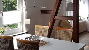 A dining area with a white table and wicker chairs, a ceiling light fixture, and a view of the outdoors. - Vacation apartment in Wermelskirchen, Bergisches Land, near Cologne and Düsseldorf (Wermelskirchen)
