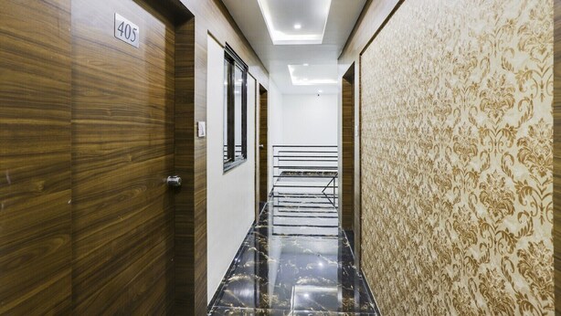 Un pasillo con una puerta de madera que indica '405', un papel tapiz decorativo y una escalera que sube a un piso superior.