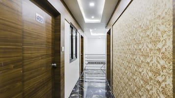 A hallway with a wooden door labeled '405', a patterned wall, and a staircase leading to an upper floor.