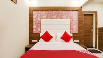 A bedroom with a brick-patterned headboard, a bed with white bedding and red pillows, and a wooden wardrobe.