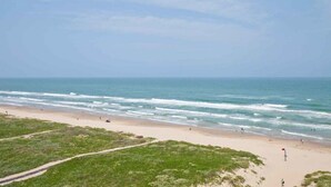 Ein Strand mit sandigem Ufer und einem Weg zum Wasser.