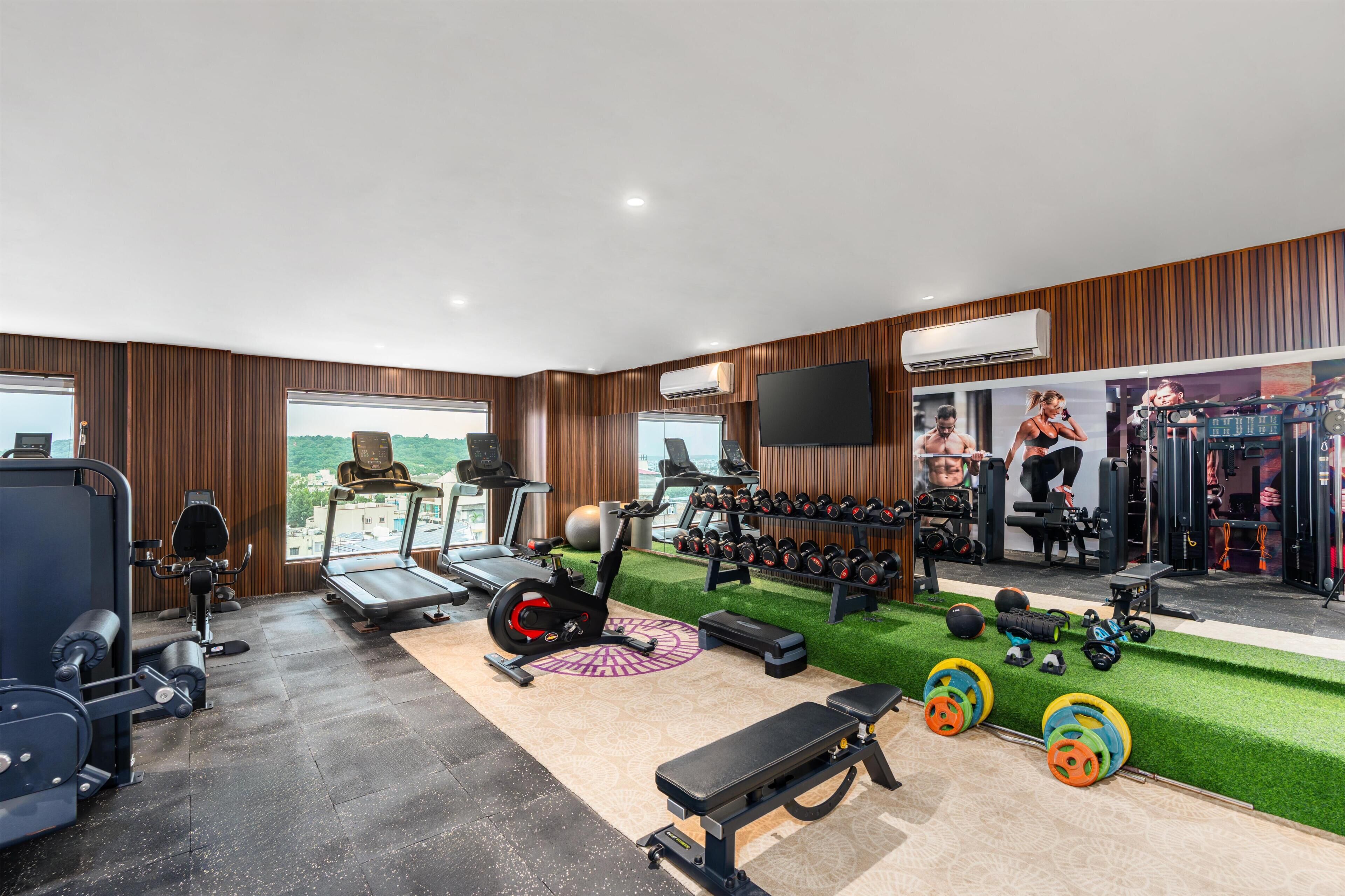 Un gimnasio con cintas de correr, máquinas de pesas y una variedad de pesas.