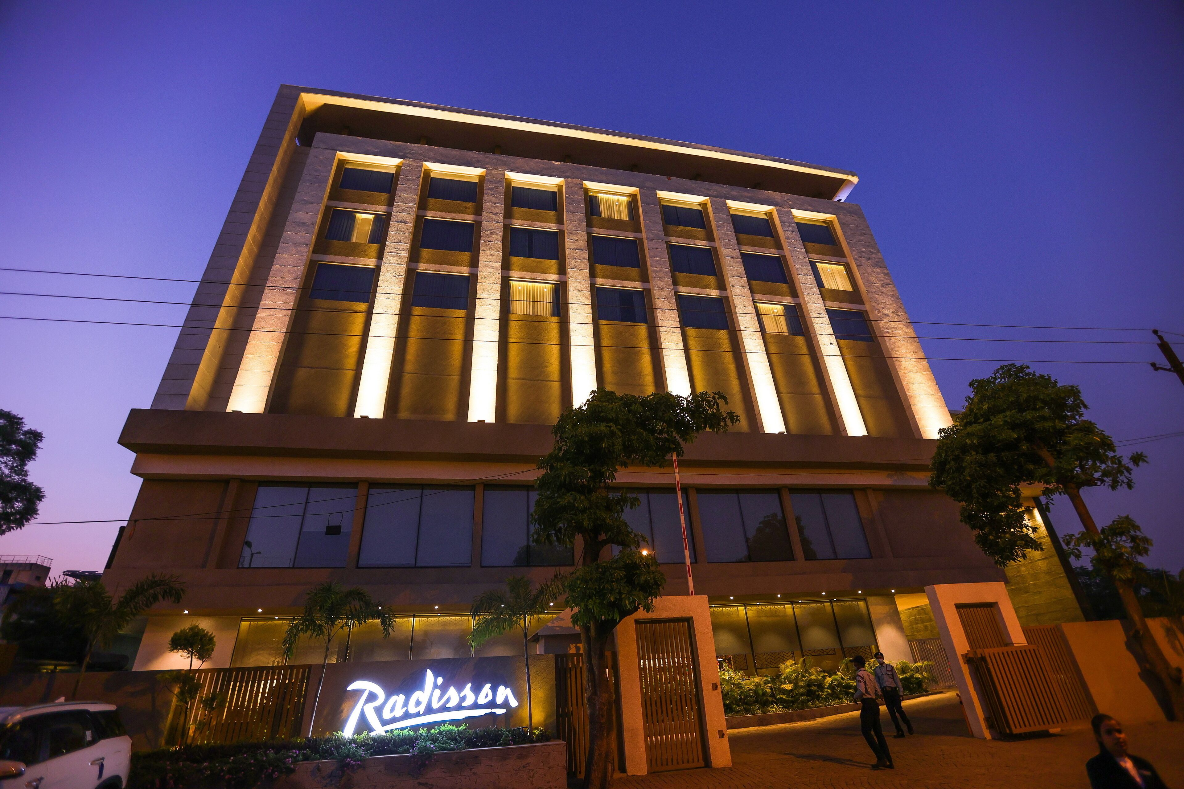 Un hotel moderno con un llamativo letrero de 'Radisson', amplias ventanas y una fachada bien iluminada.
