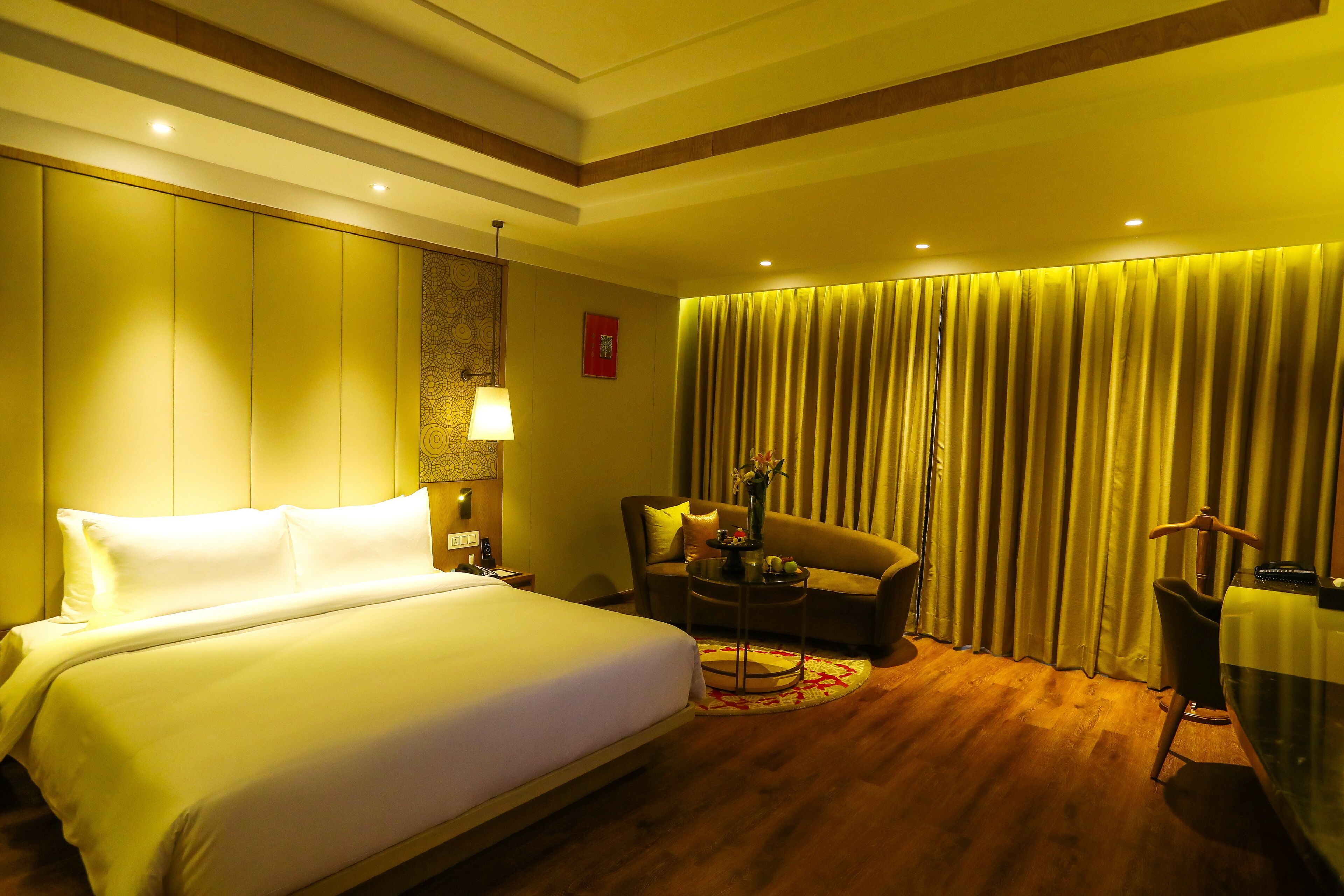 Een hotelkamer met een groot bed, een bank, een stoel, een lamp en een gordijn.