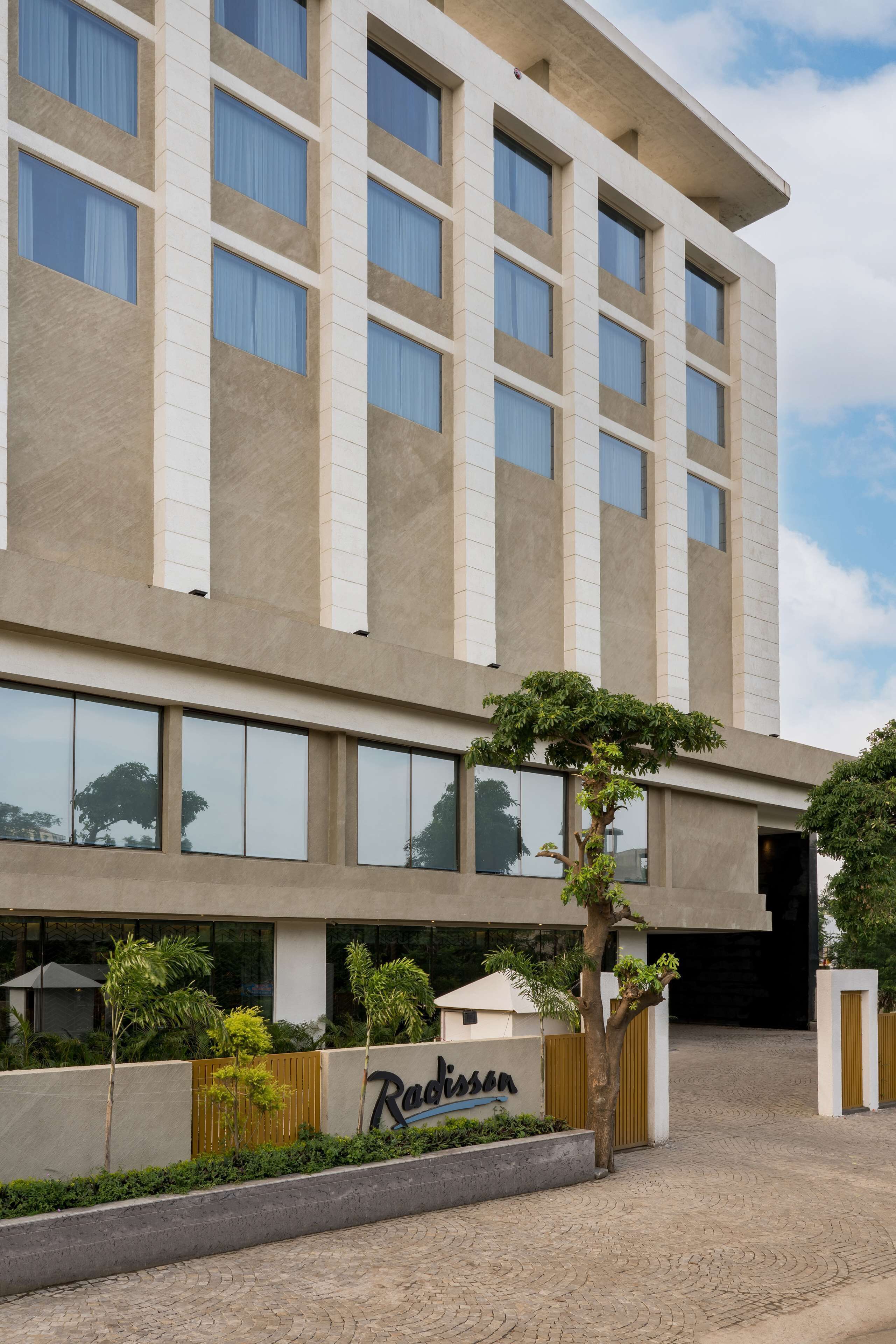 A modern hotel building with a flat facade, large windows, and a name sign on the ground floor.