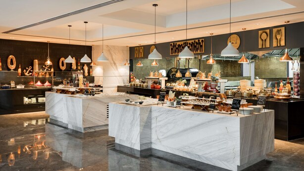 A modern, well-lit food display area with marble counters and hanging pendant lights. - Radisson Bhopal (Bhopal)