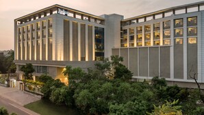 A modern hotel with a prominent entrance, large windows, and a well-maintained garden area. - Radisson Bhopal (Bhopal)