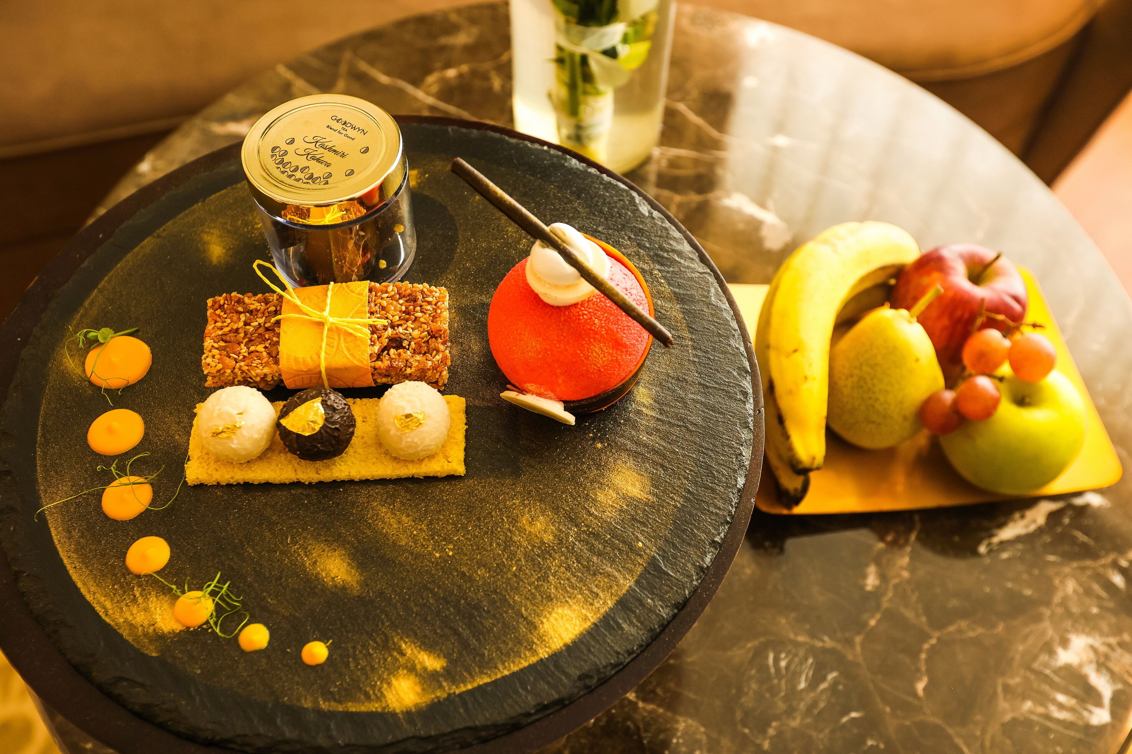 Une assiette de desserts avec divers confiseries et une présentation de fruits sur une table.