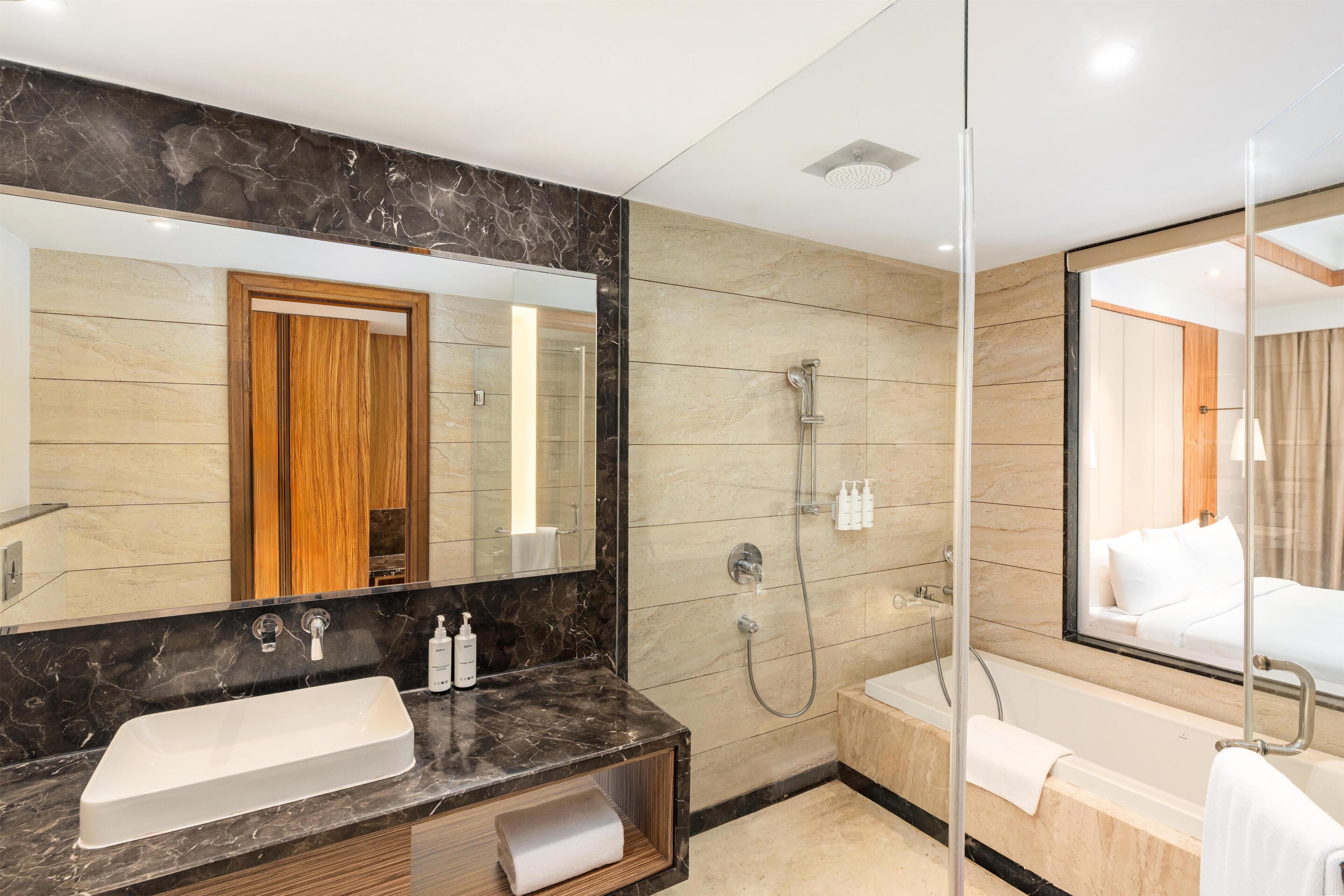 A modern bathroom with a large mirror, a sink, a shower, and a bathtub.