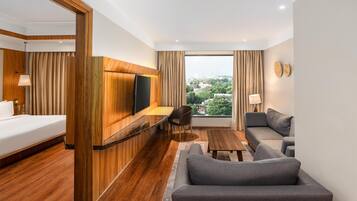 A hotel room with a bed, a desk, a sofa, and a large window with a city view.