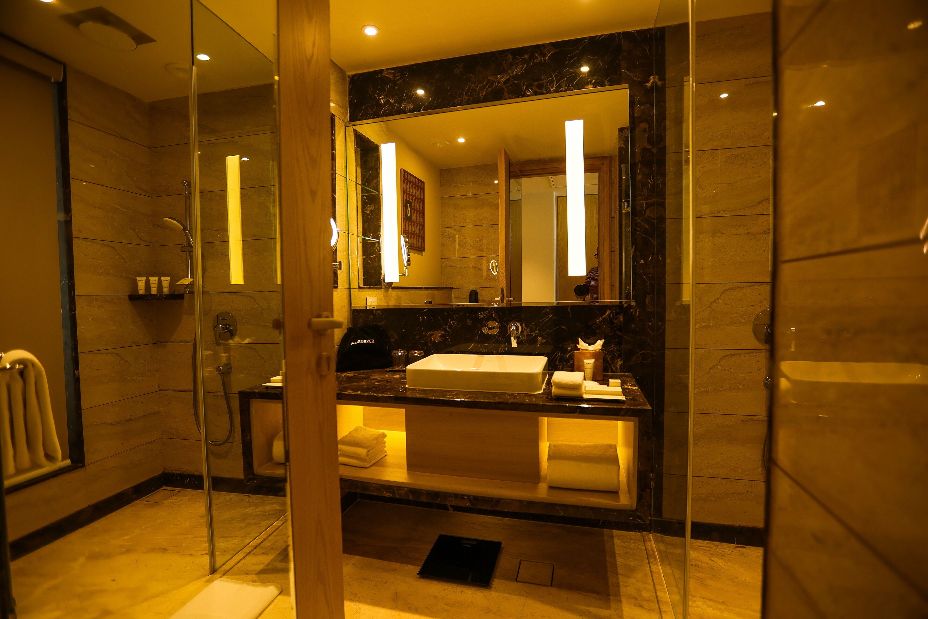 A modern bathroom with a glass-enclosed shower, a marble countertop, and a large mirror.