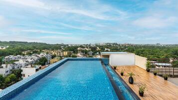 A rooftop swimming pool with a view of a cityscape.