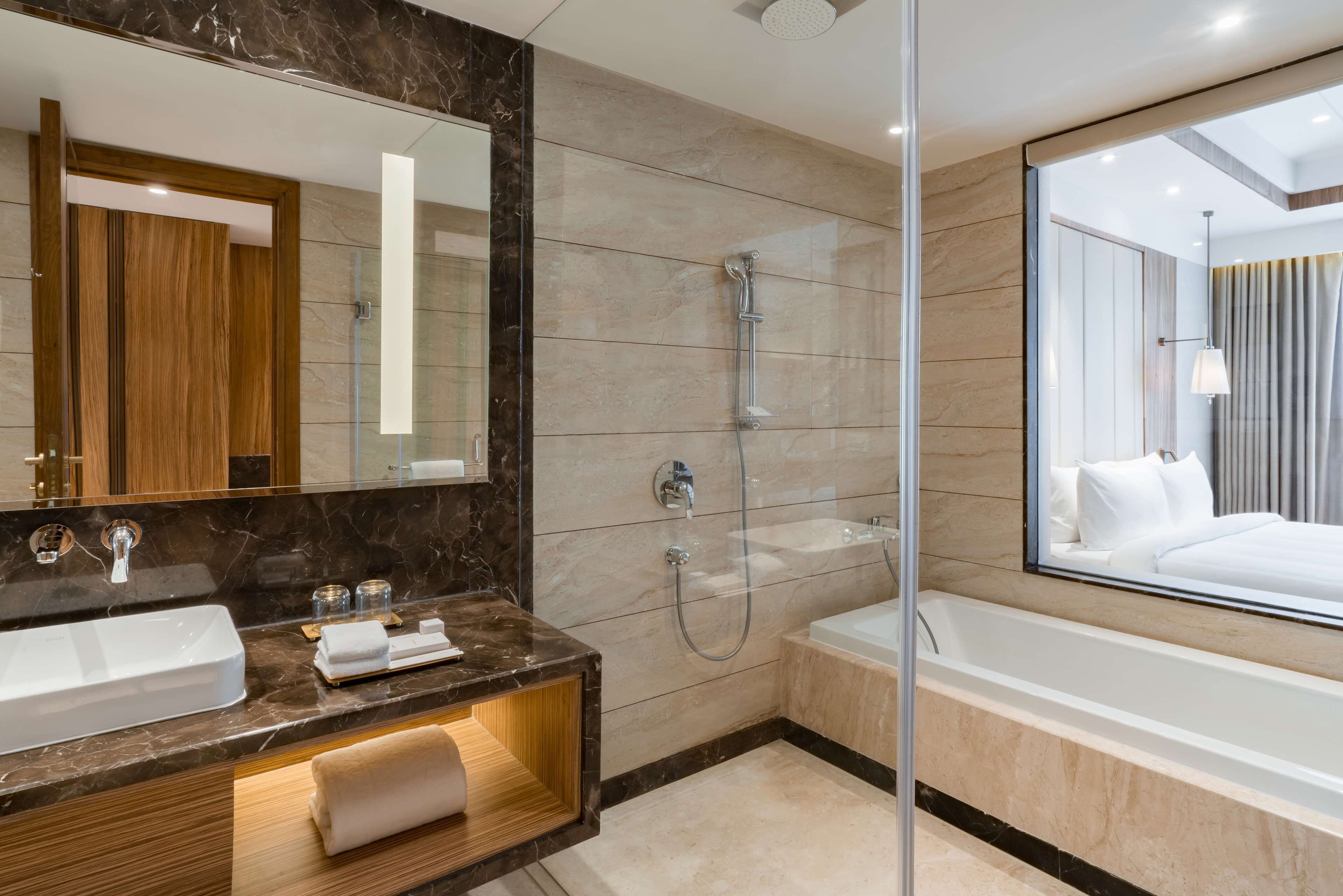 Une salle de bain moderne avec un grand miroir, deux lavabos, une douche et une baignoire.