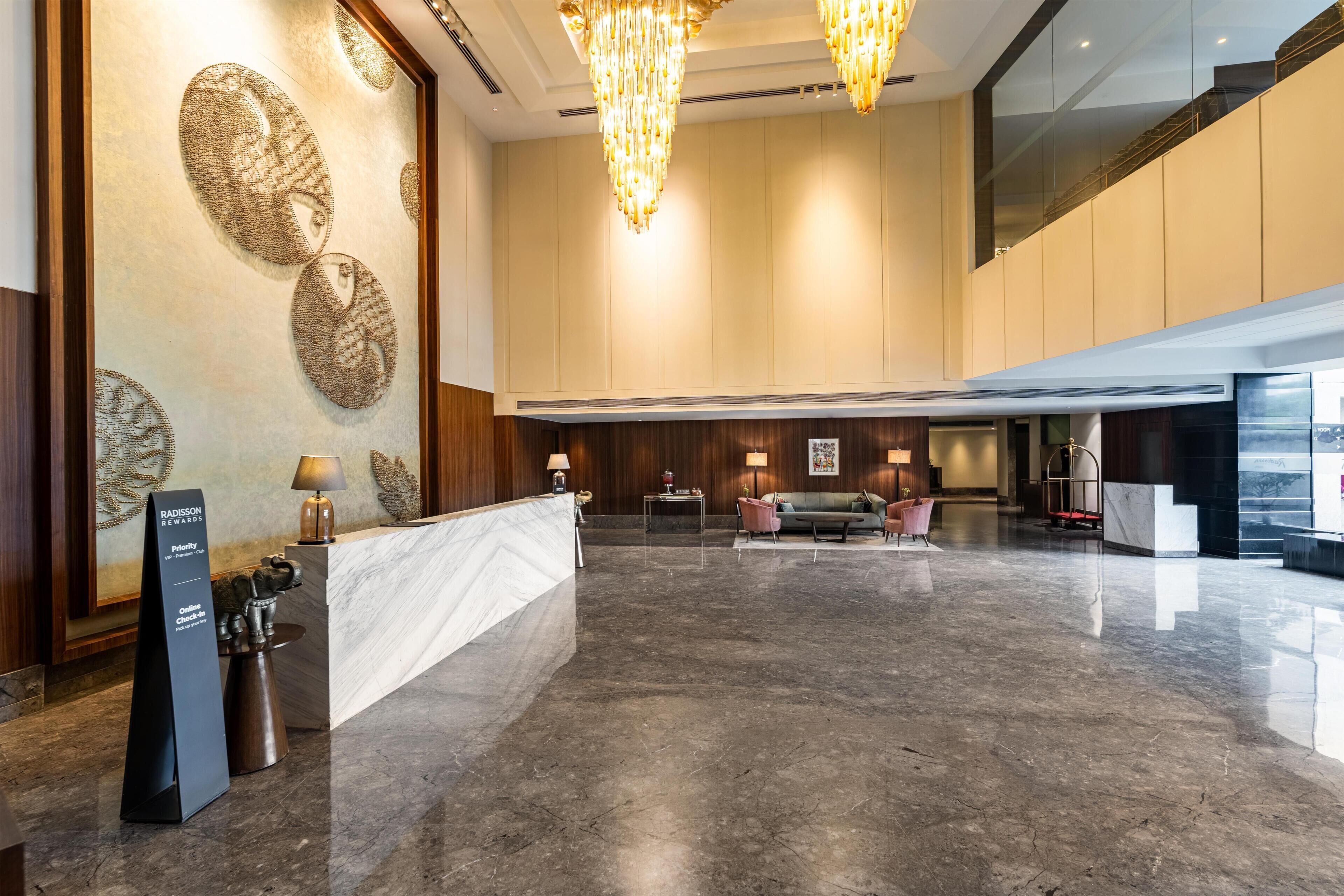 Un hall espacioso con un mostrador de recepción de mármol, una araña y una zona de estar con sofá y sillones.