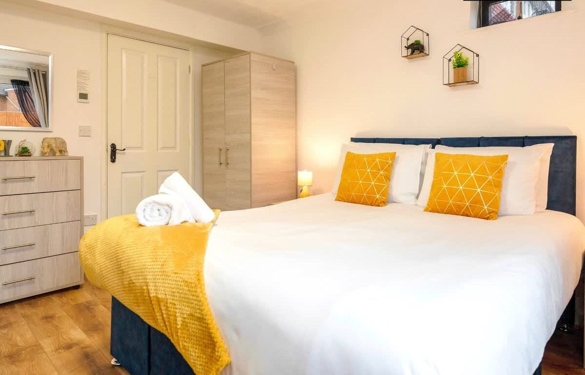 A hotel room with a bed, a wardrobe, a mirror, and a door.