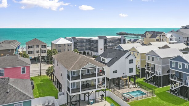 Un quartier résidentiel situé sur la côte, avec des immeubles à plusieurs étages, une jetée et une piscine.