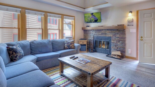 A living room with a stone fireplace, a blue sofa, and a coffee table. - The Blue Bear | Trails, Golf, Pool & Hot Tub - Near Town (Durango)