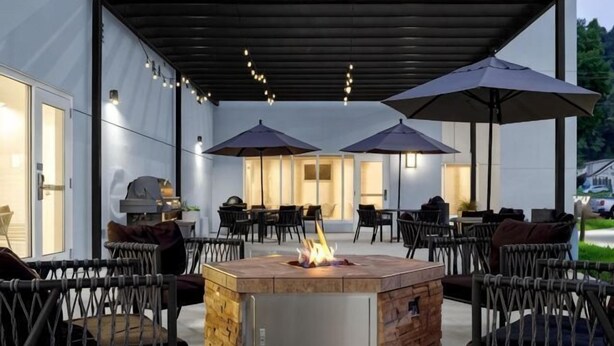 Un patio al aire libre con un brasero, asientos exteriores y sombrillas.