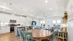 Une cuisine moderne avec des meubles blancs, une table à manger en bois et un ventilateur de plafond.