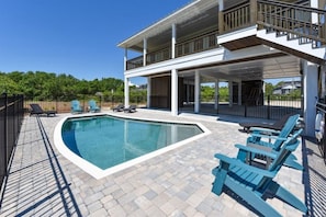 Ein modernes Haus mit Swimmingpool, Sitzgelegenheiten im Freien und einer überdachten Terrasse.