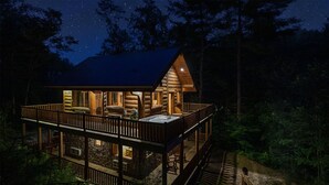 A log cabin with a balcony and hot tub, surrounded by trees. - Black Bear Pond log cabin (Almond)