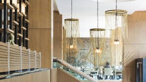 Un interior moderno con una escalera, asientos de listones de madera e iluminación colgante.
