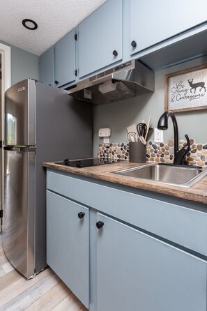 Una cocina con refrigerador de acero inoxidable, horno empotrado, encimera de granito y salpicadero con azulejos multicolores.