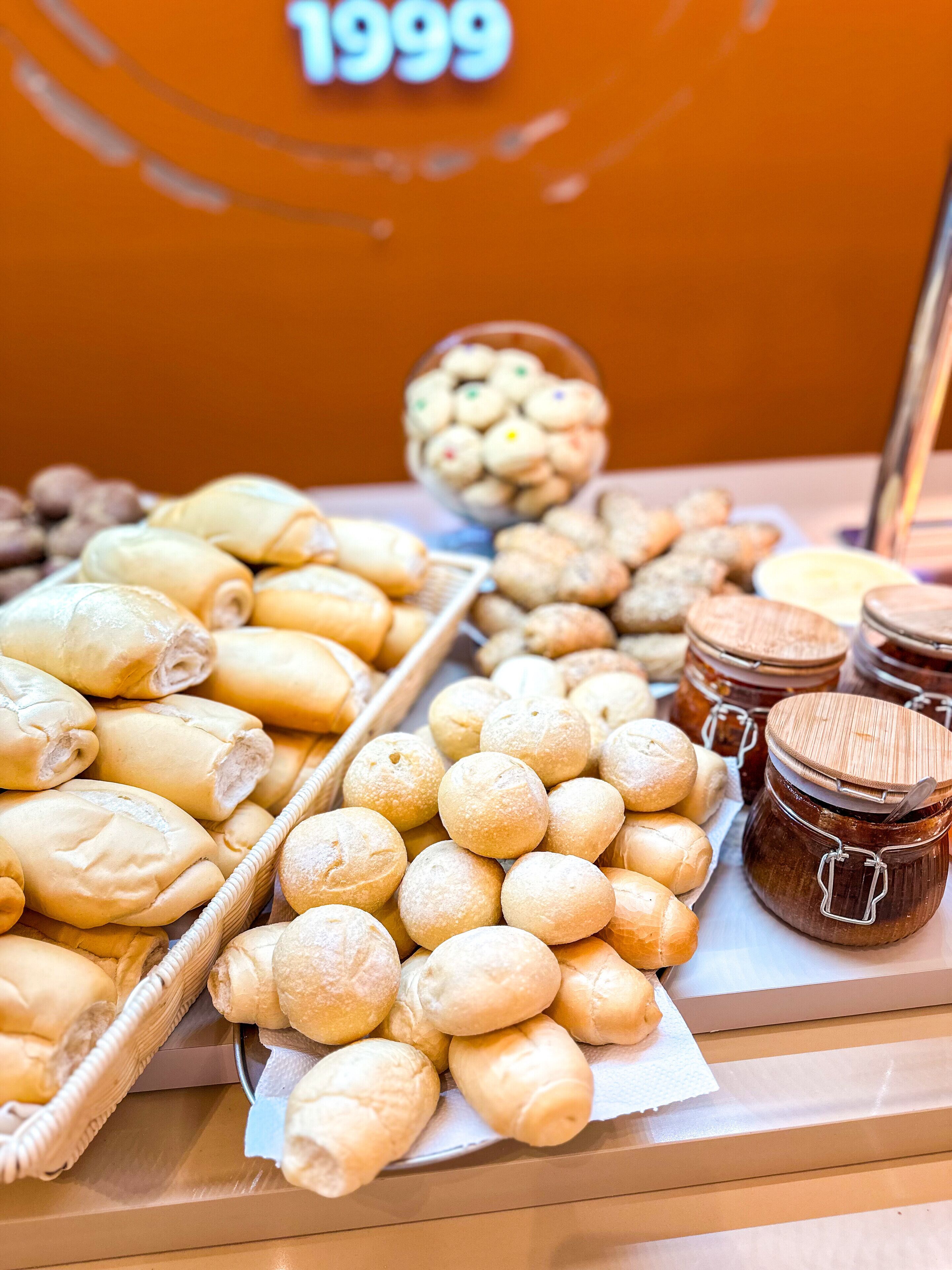 Una exhibición de panadería con bollos, pasteles y frascos de mermelada.