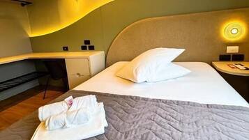 Una habitación de hotel con cama, escritorio y mesita de noche.
