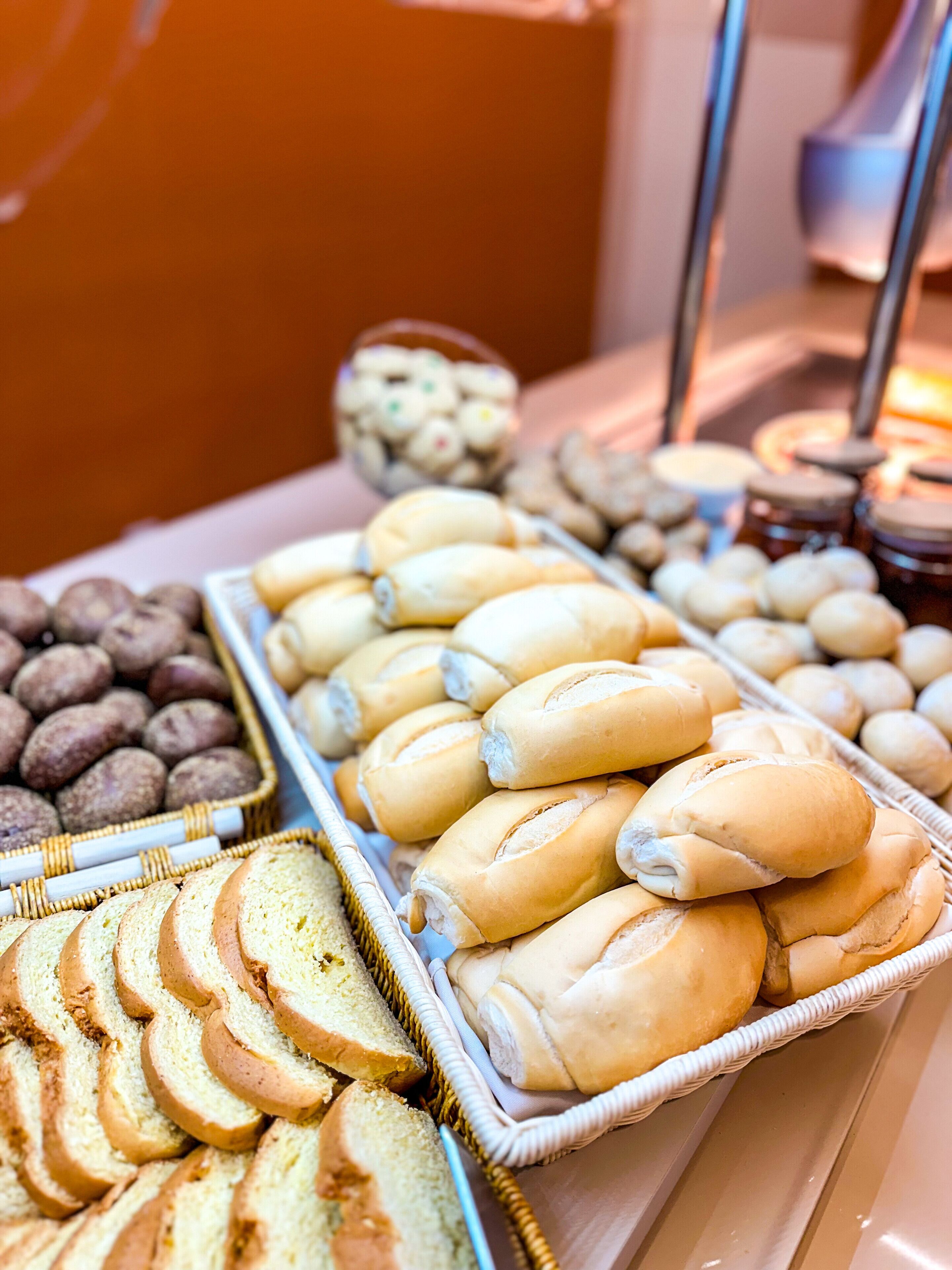 A buffet with various baked goods including bread rolls, sliced bread, and cookies.