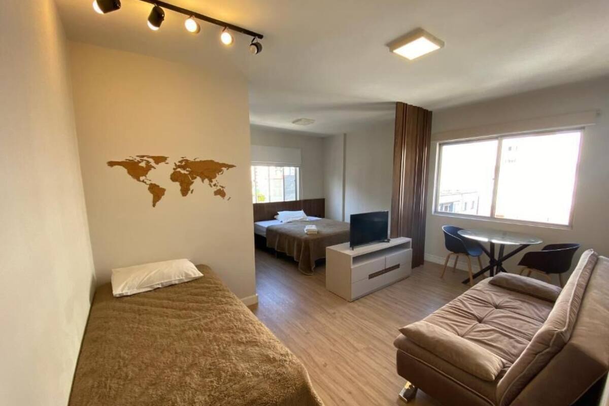 A compact hotel room with a bed, a sofa, a TV, and a small dining table.