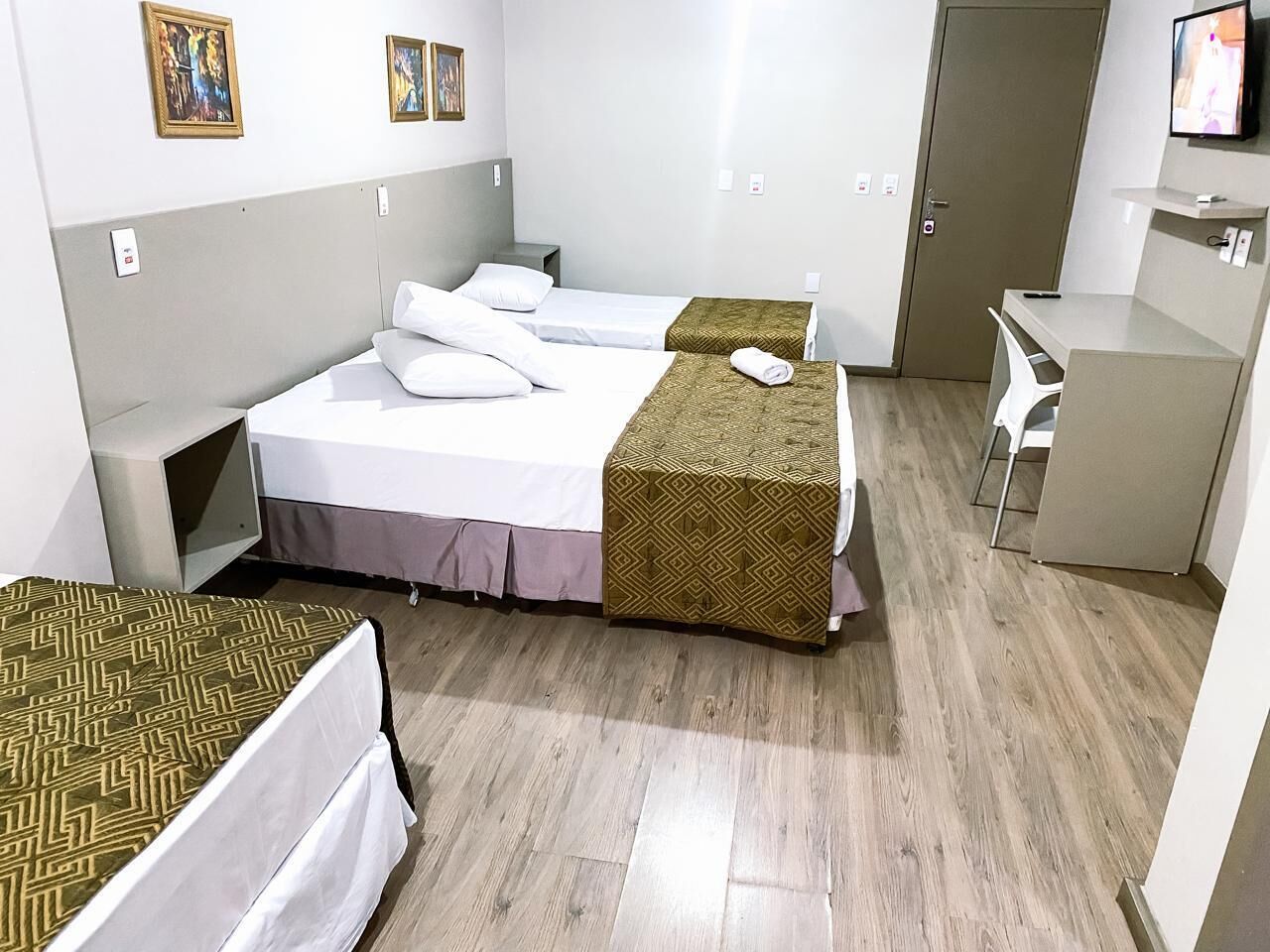 Une chambre d’hôtel avec deux lits simples, un bureau, une chaise et un téléviseur.