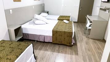 Habitación de hotel con dos camas individuales, un escritorio, una silla y un televisor.