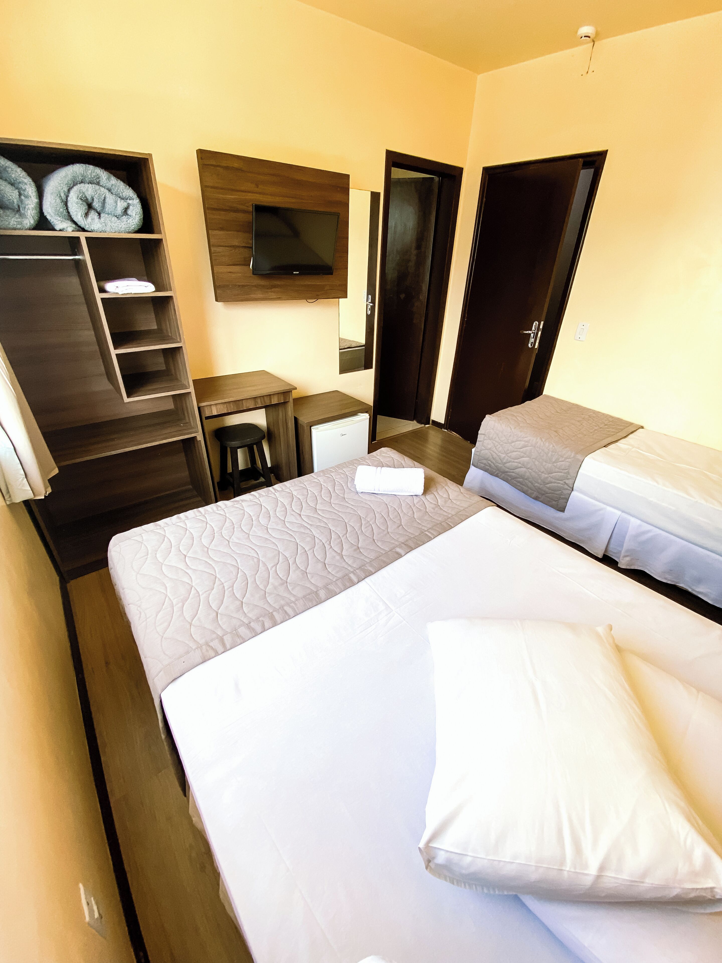 Hotellihuone, jossa on sänky, työpöytä, tuoli, televisio ja vaatekaappi.