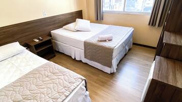 Une chambre d’hôtel avec deux lits, un plancher en bois, une fenêtre avec des rideaux et un climatiseur fixé au mur.