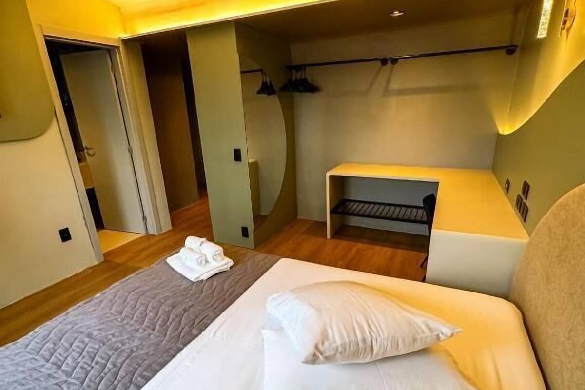 A hotel room with a large bed, a bench, and a wardrobe.