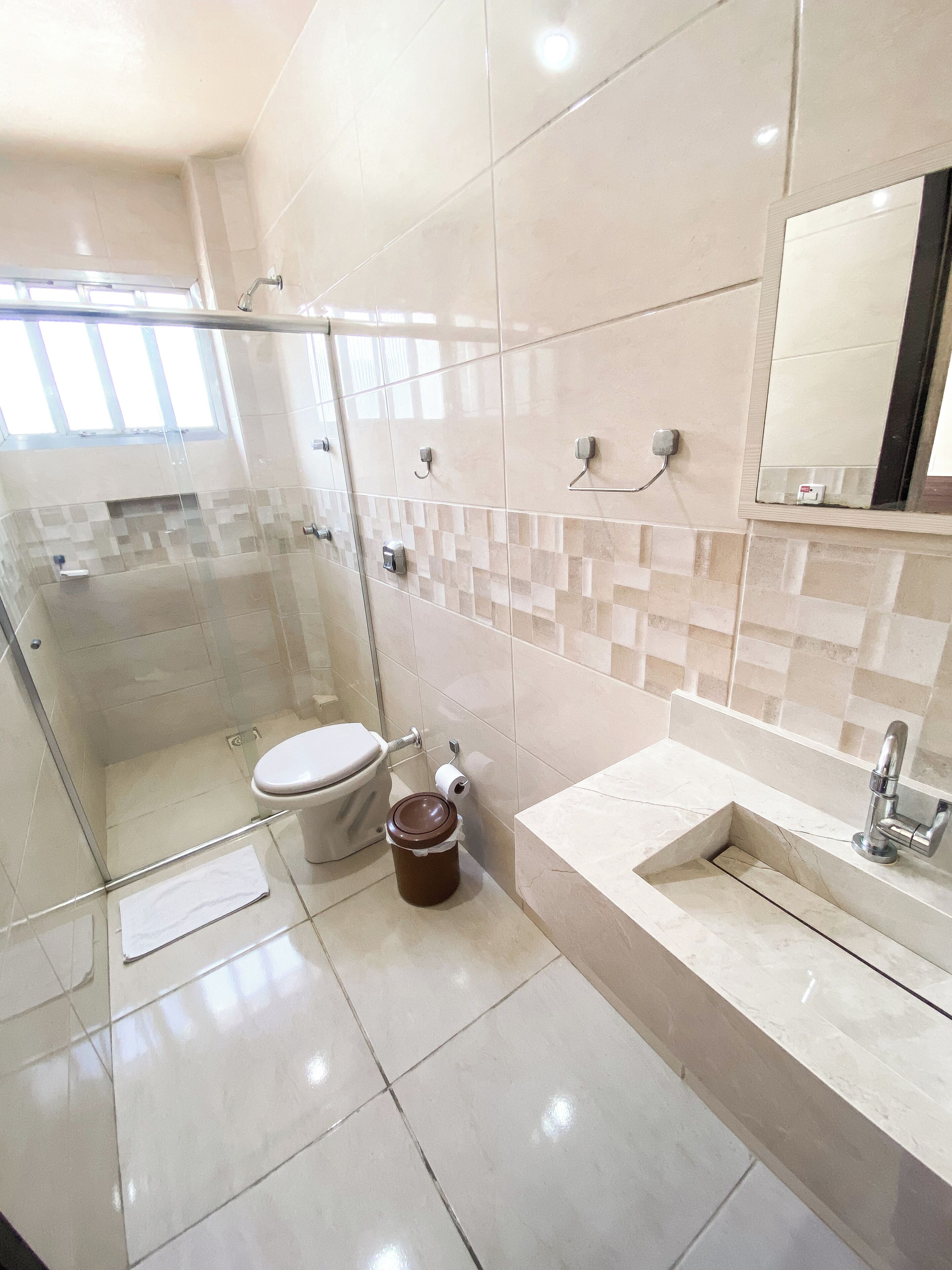 Un baño moderno con cabina de ducha de vidrio, inodoro, lavabo y espejo.