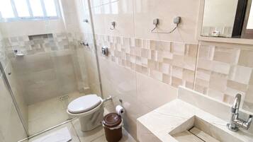Un baño moderno con cabina de ducha de vidrio, inodoro, lavabo y espejo.