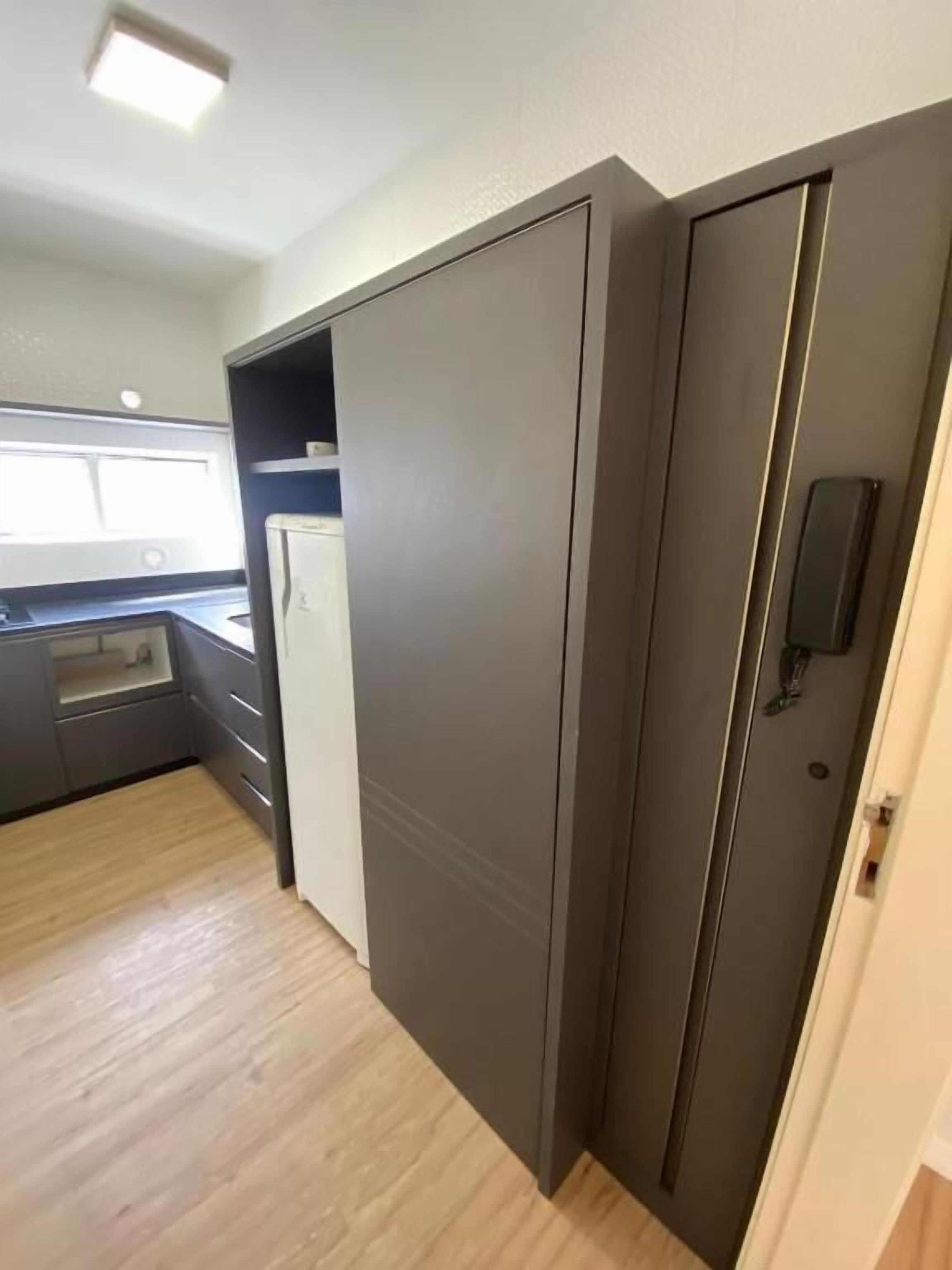 A compact kitchen with a built-in refrigerator, a microwave, and a sink.