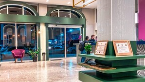 A lobby with a reception desk, a red chair, and a large pillar. - Hotel Zata Econômico (Criciuma)